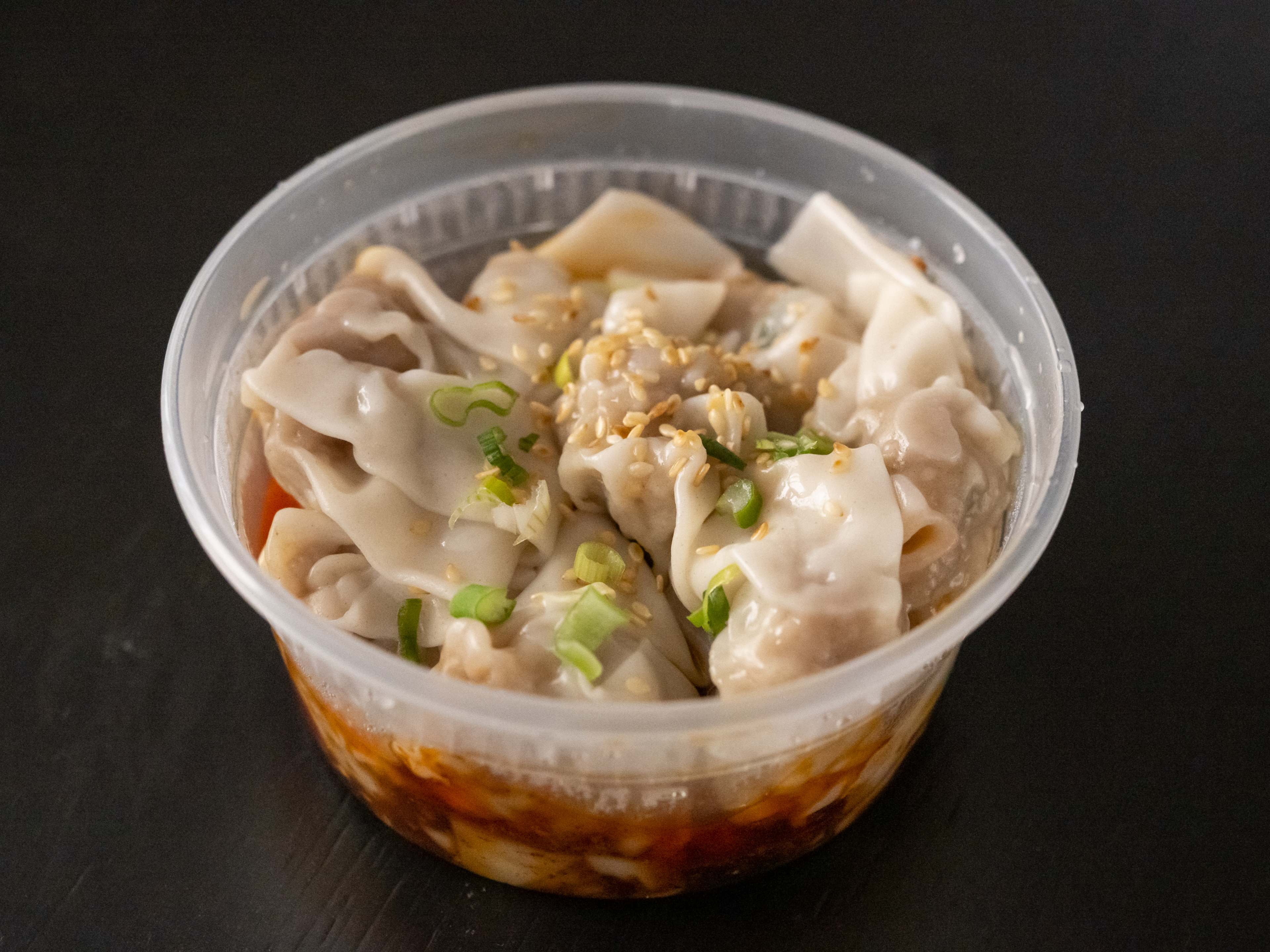 Takeout tub full of wontons in chili oil