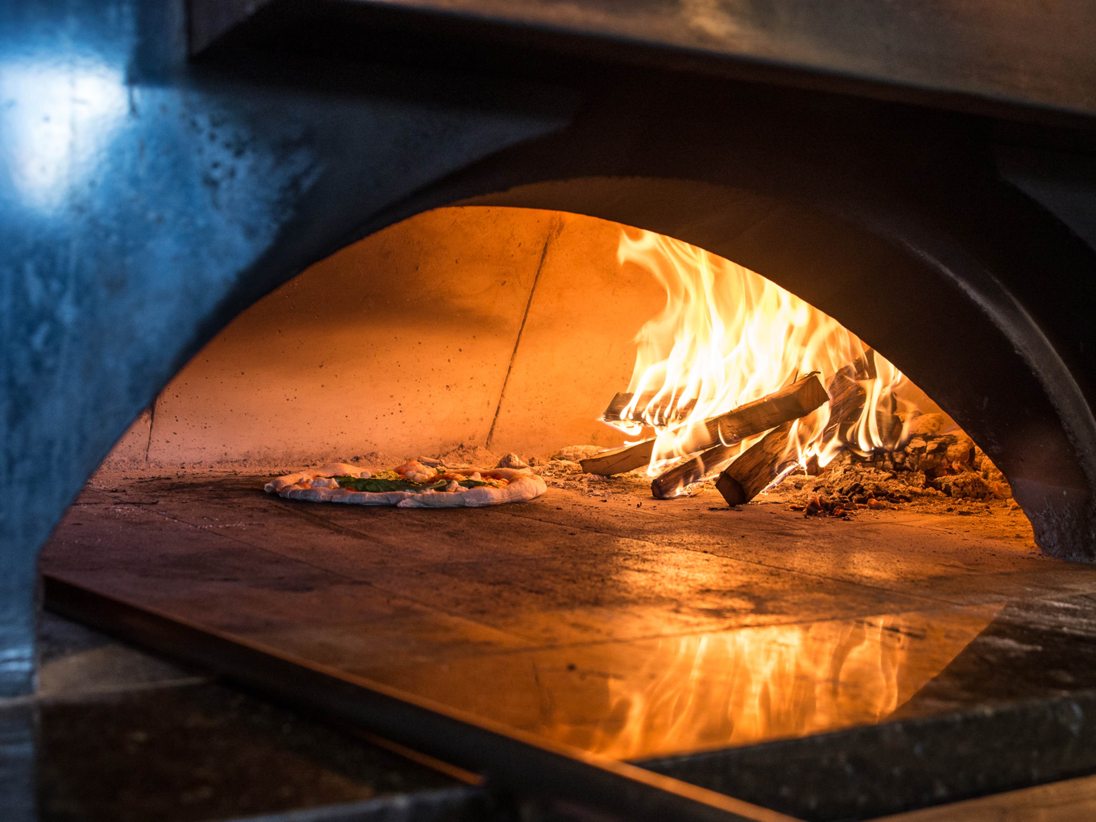 A pizza inside a wood-fired oven