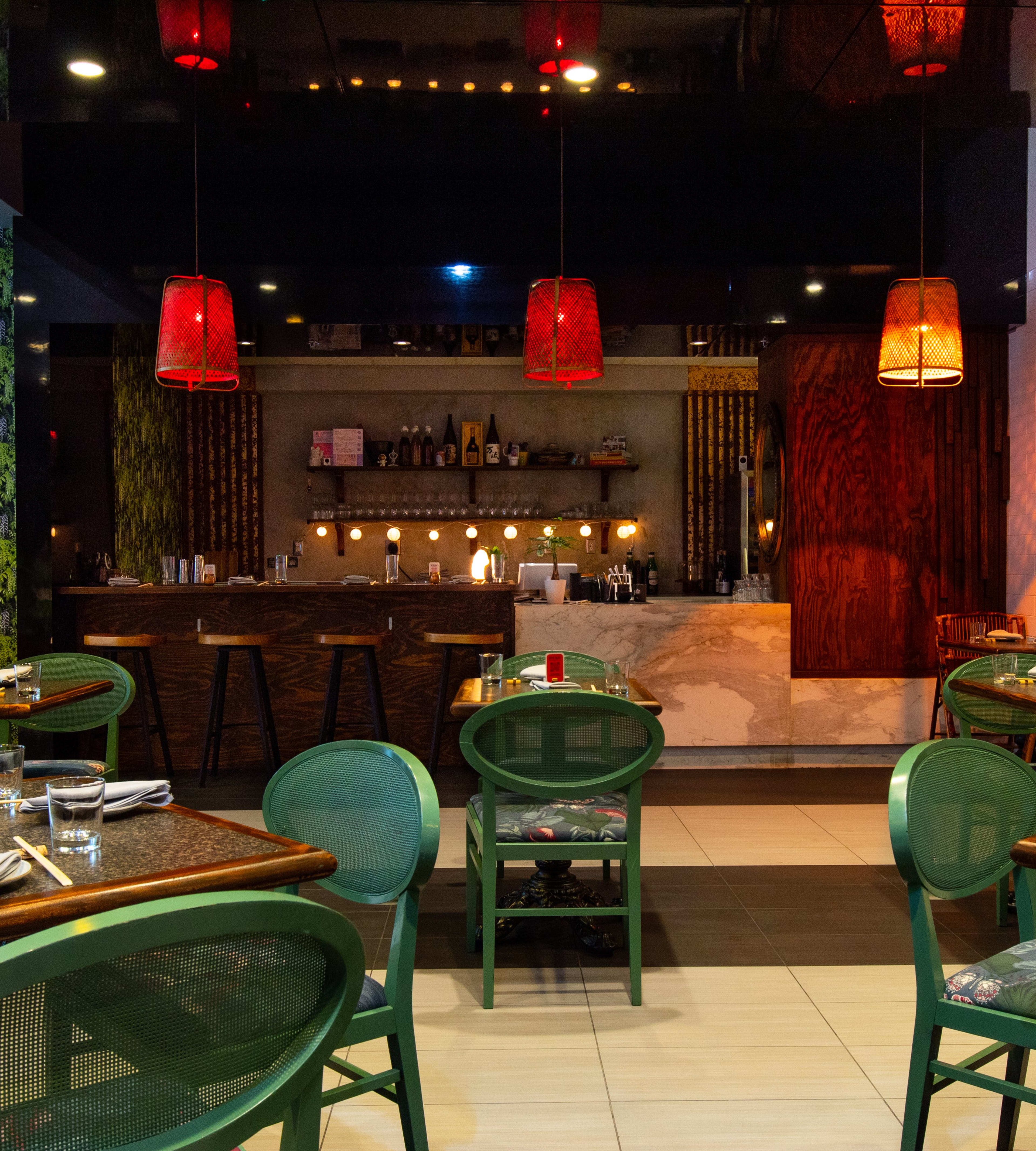 Tables with green chairs in a dark dining room.