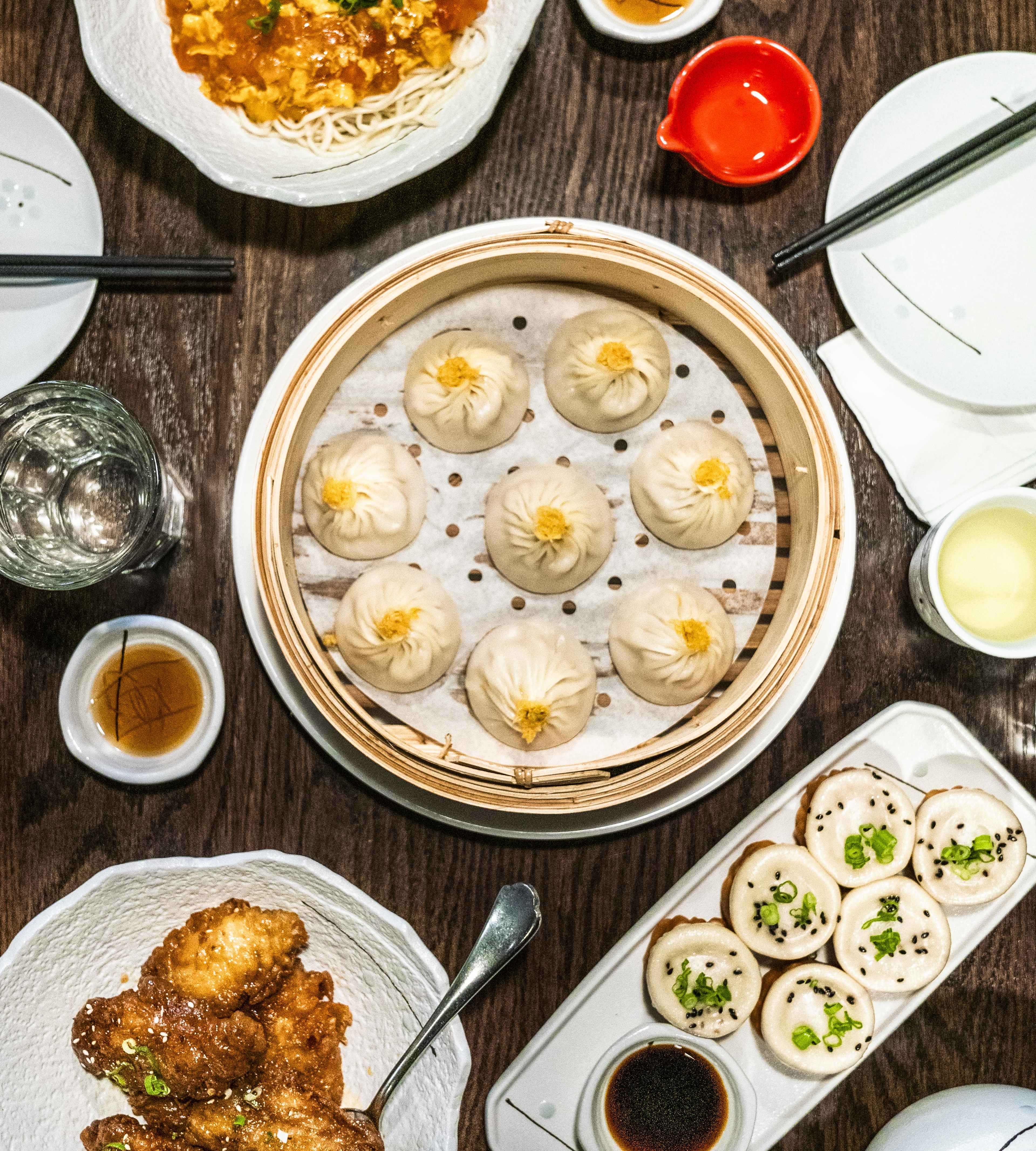 A spread of xiao long bao, wings, noodles, and shengjianbao at Dumpling Story