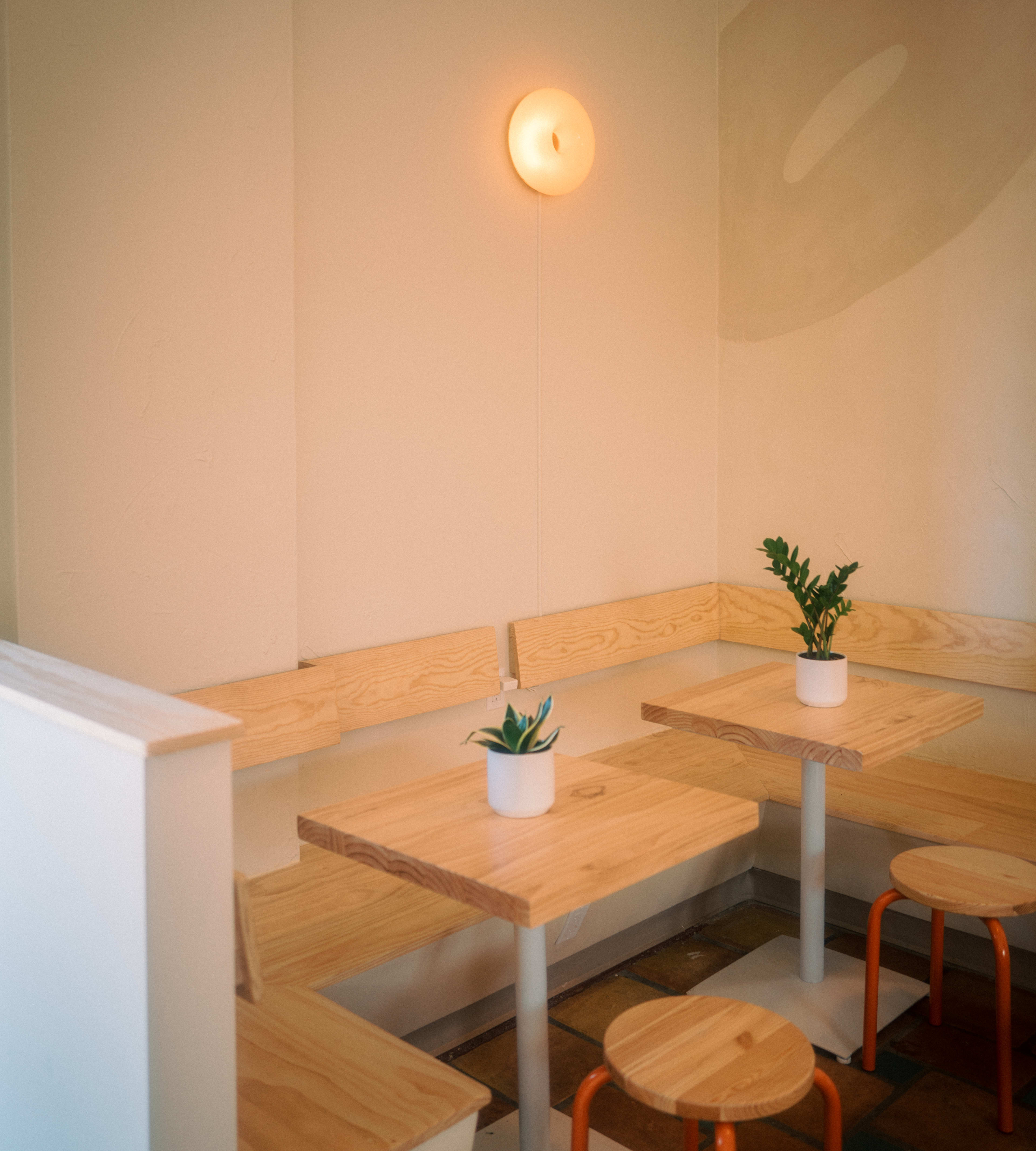 Corner tables and bagel paintings on the wall at Hella Bagels