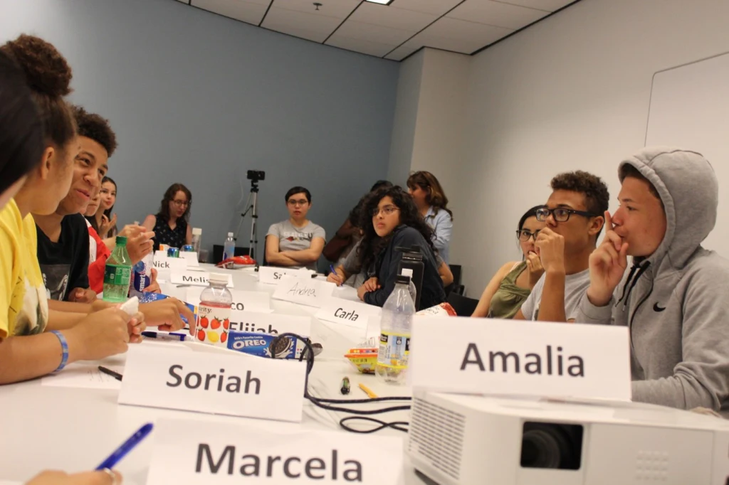 A group of teenage students gather at a table.