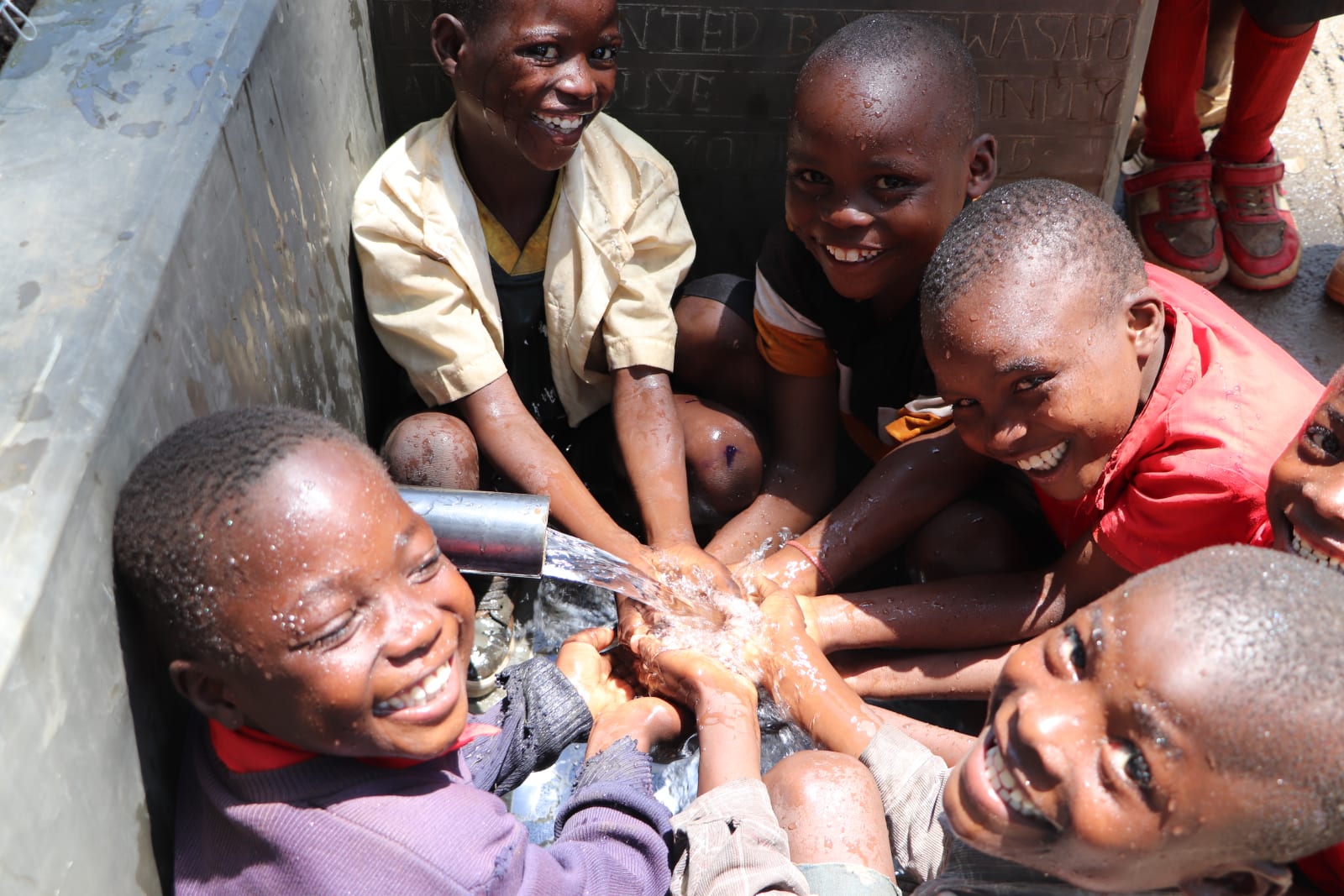 Students and community members celebrating at a rehabilitated water point in Kenya