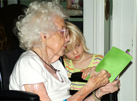 An elderly lady reading to a child