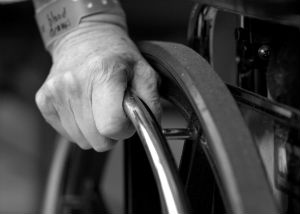 An elderly hand on a wheelchair