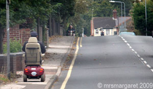 A mobility scooter going down the pavement