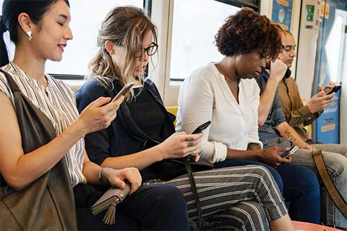 People on a train all looking at their smartphone.