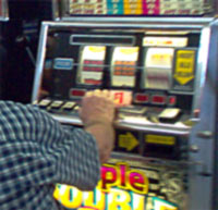 A man playing a slot machine in a gaming area.