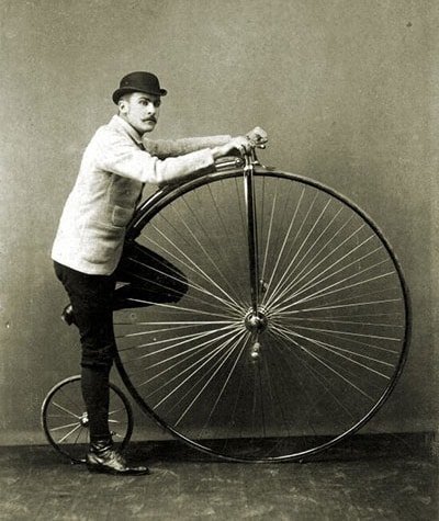 Bicycle Penny Farthing 1880s man standing with a penny farthing bicycle from the 1880s