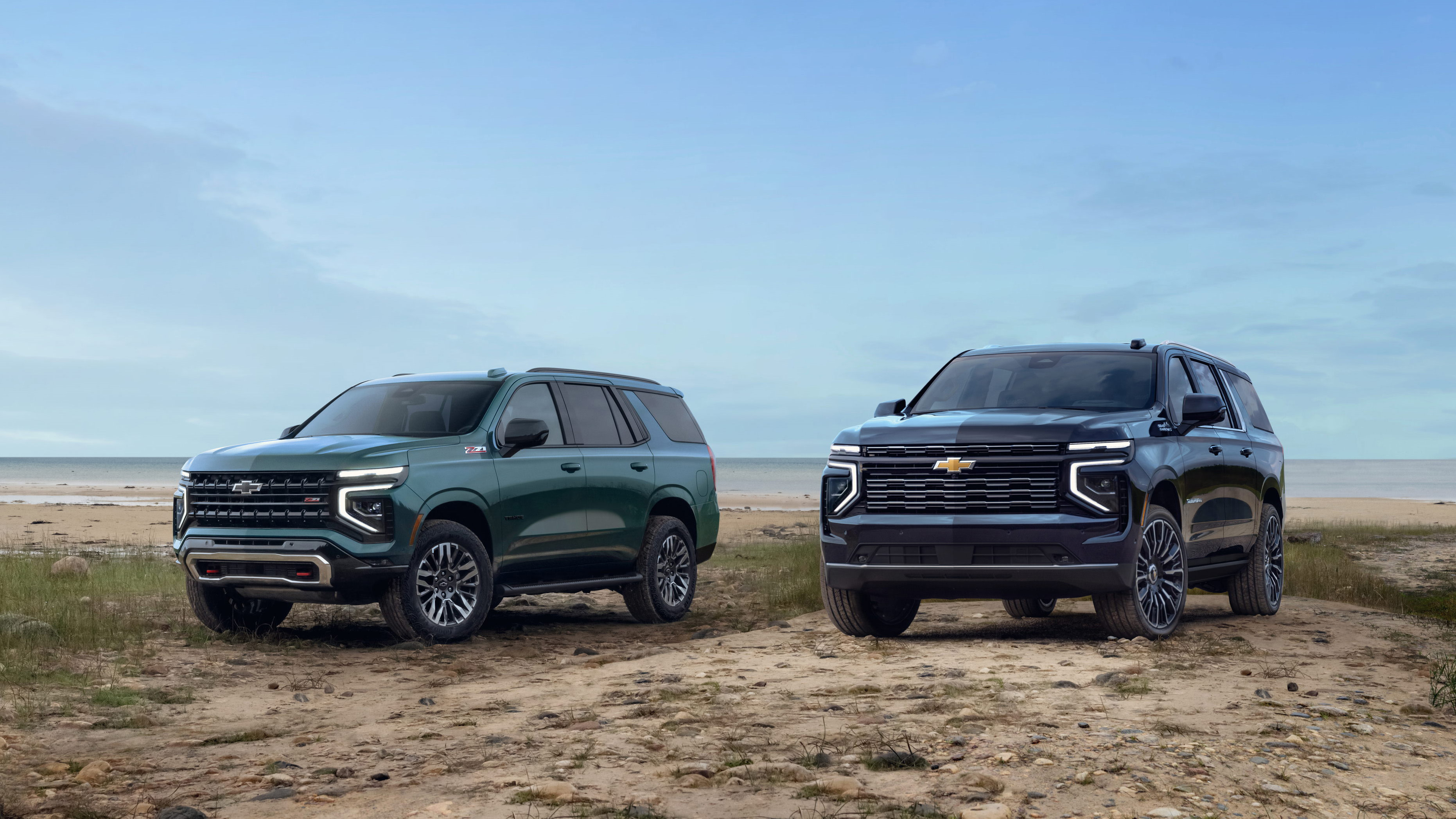 Group shot of 2025 Tahoe Z71 (left) and 2025 Suburban High Country shown on the beach