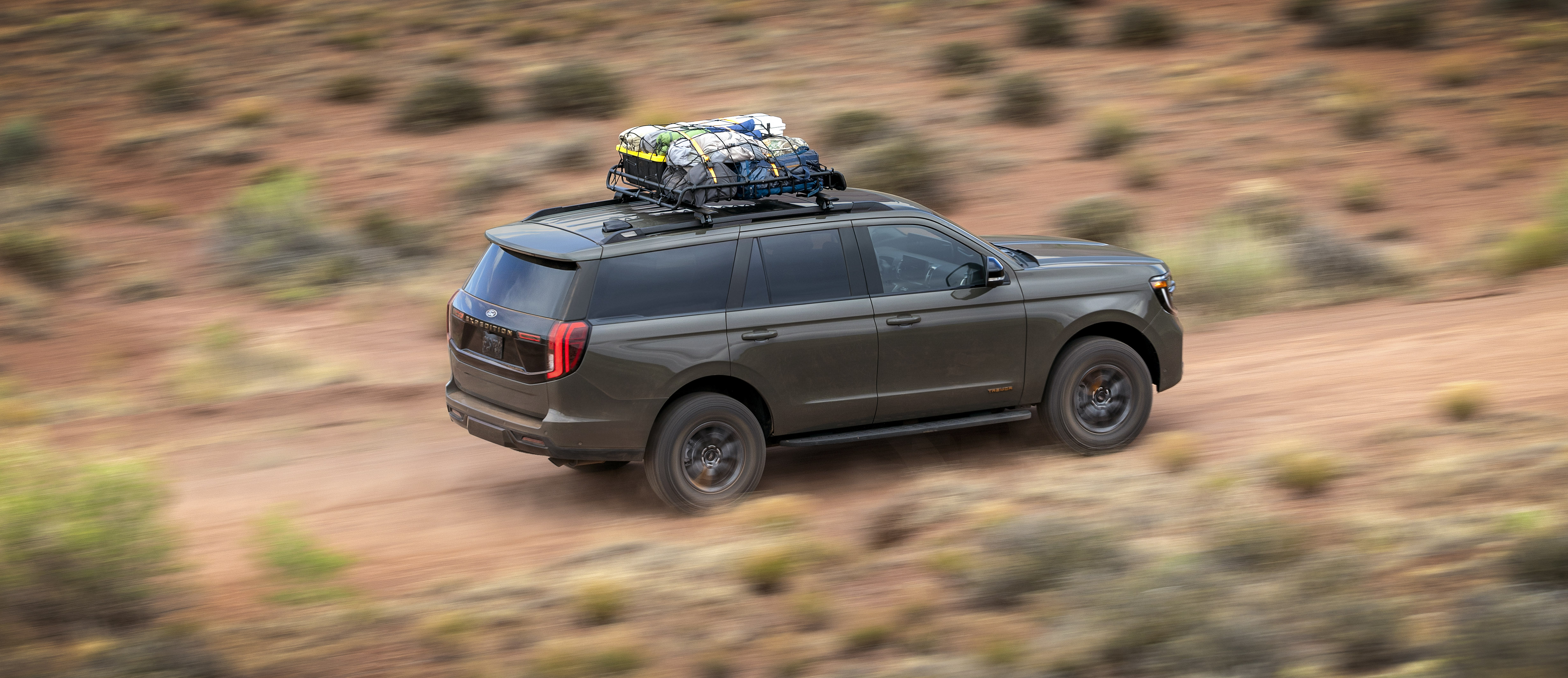 Ford Expedition Tremor driving through the desert at speed with luggage on its roof rack