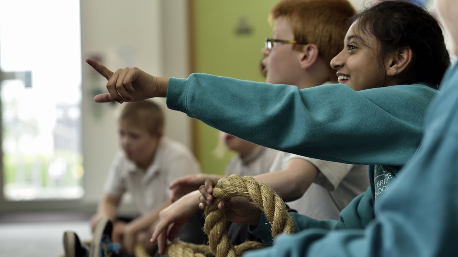 School children wearing green jumpers actively participating in a workshop session