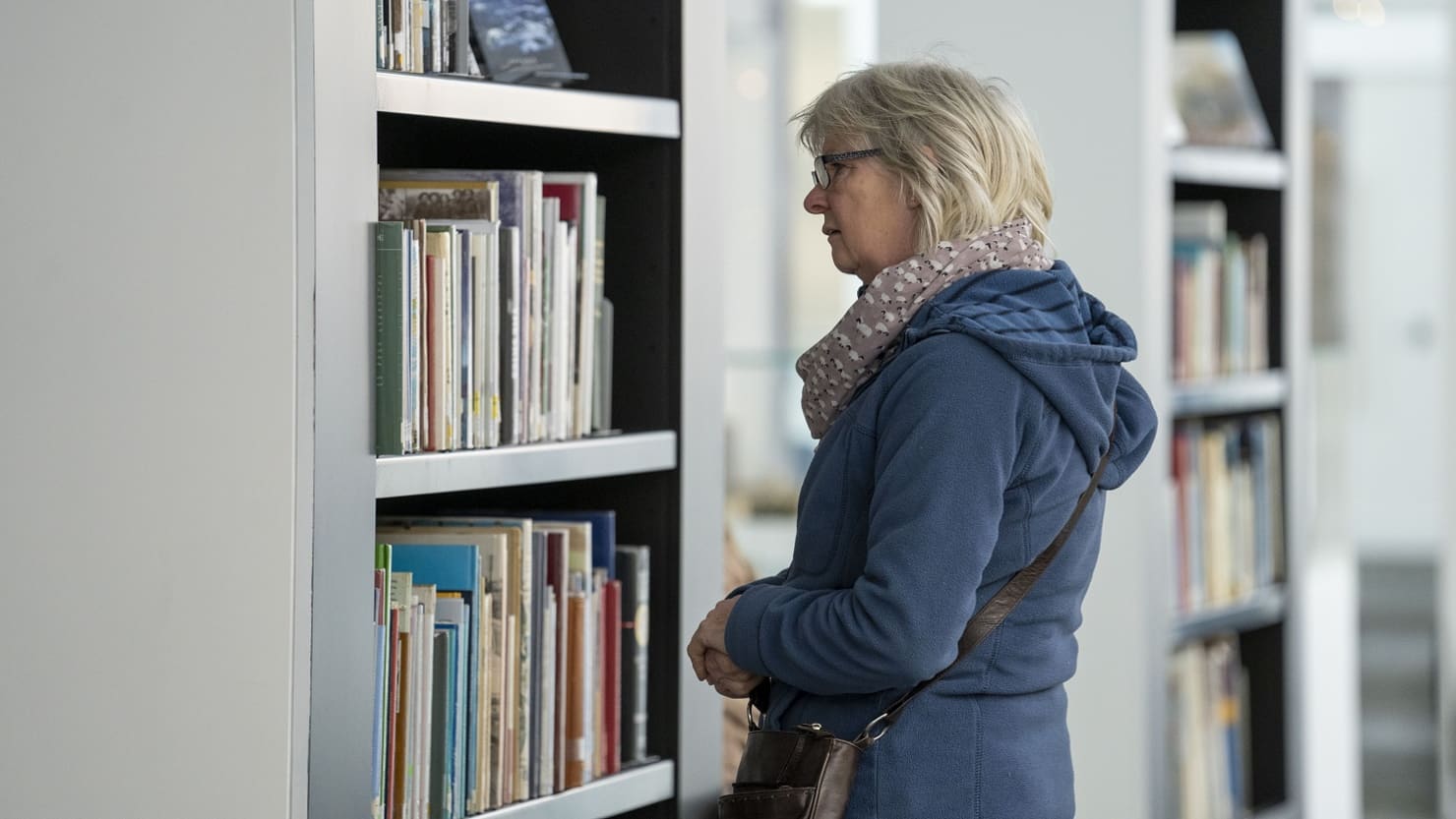 A female looking at books on a shelf in the Active Archives gallery at The Box