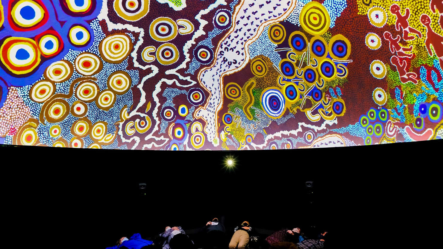 People watch a projection on the ceiling. Image © Getty.