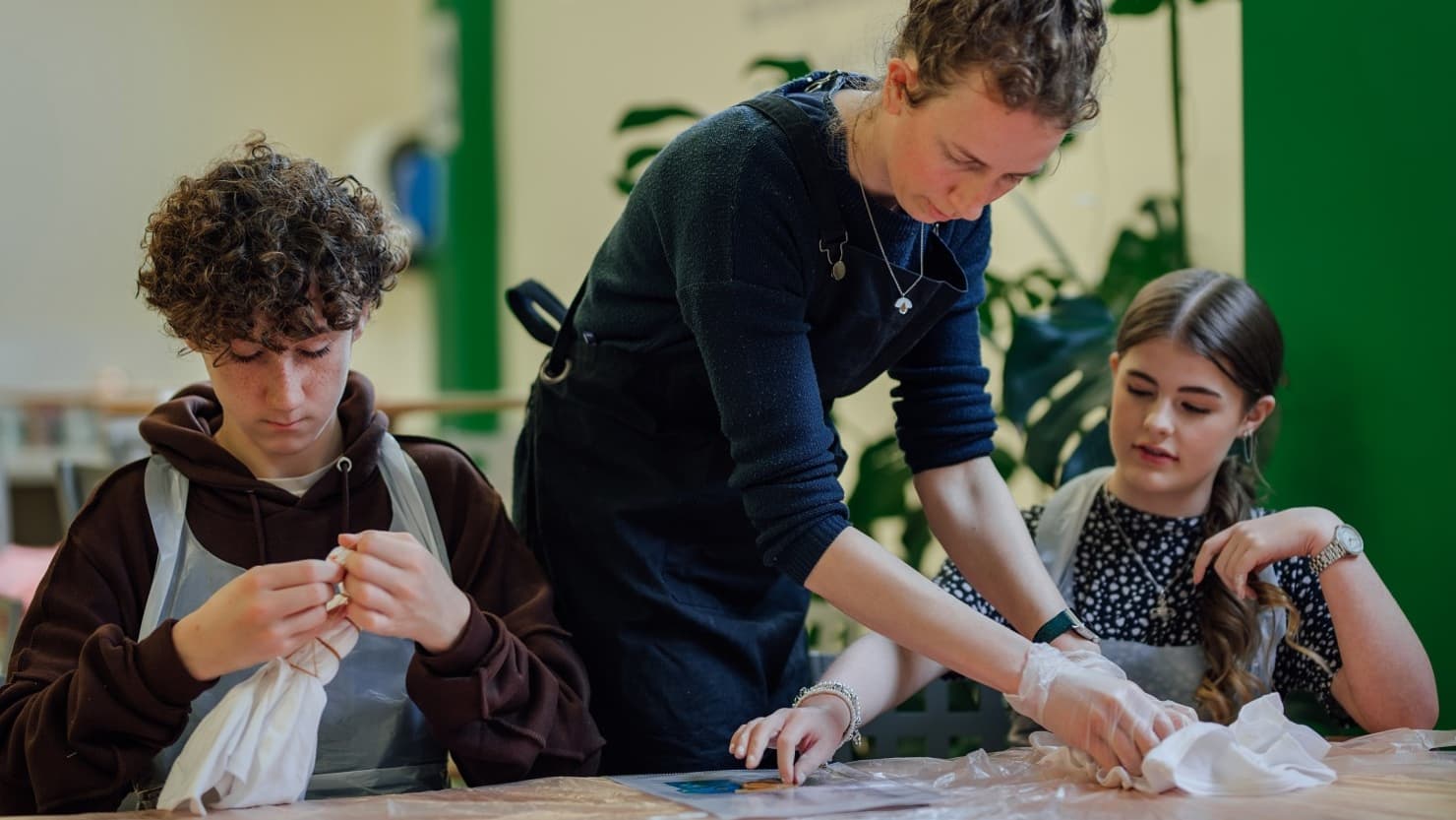 Three teenagers cutting fabric