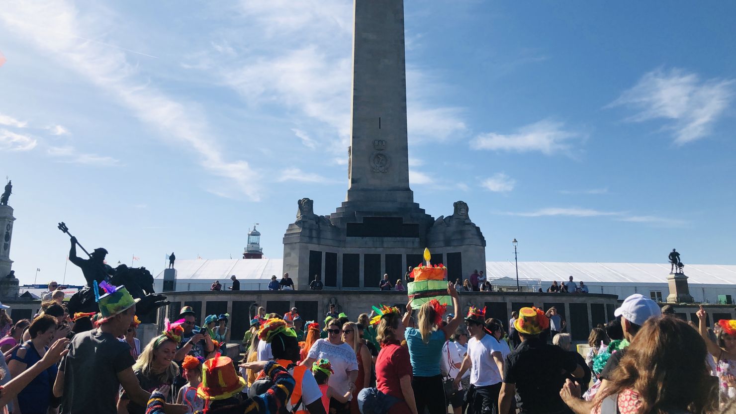 A community procession standing in front of the Royal Naval war memorial on Plymouth Hoe