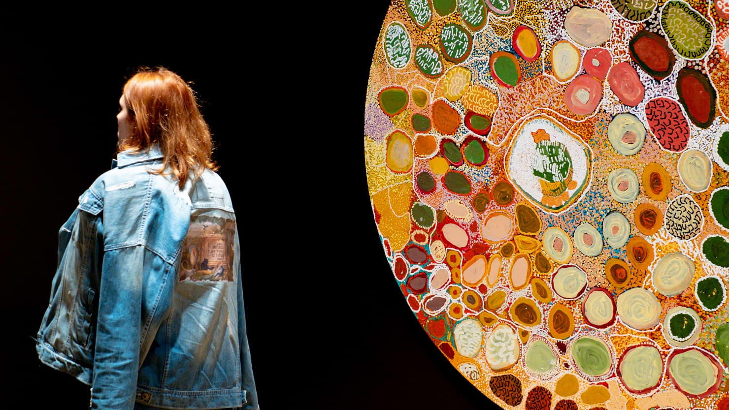 A female visitor looks at a large circular artwork on a wall. Image copyright Getty.