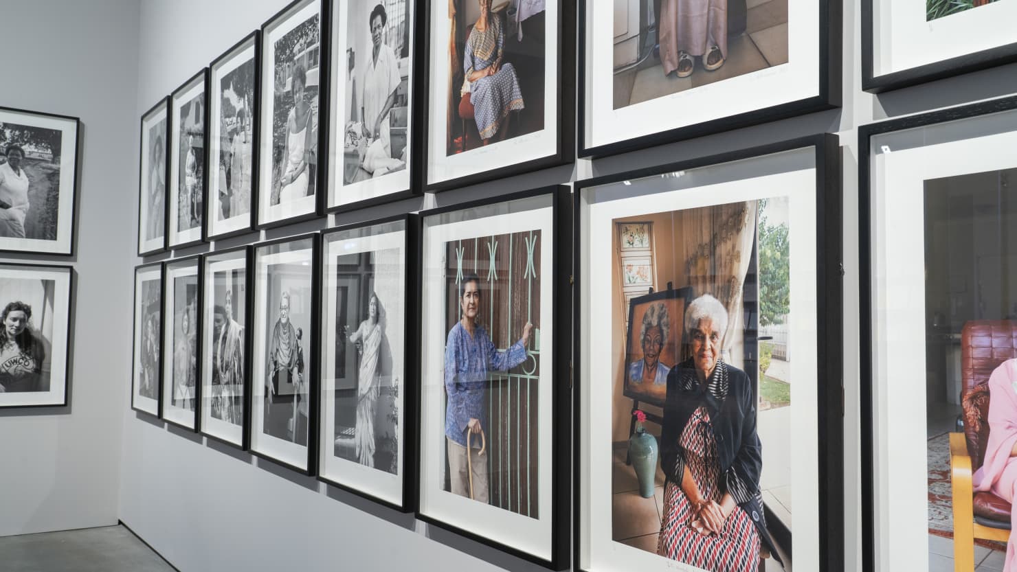 Photograph showing a photographic female portraits on display, with black and white to the left and colour photos to the right