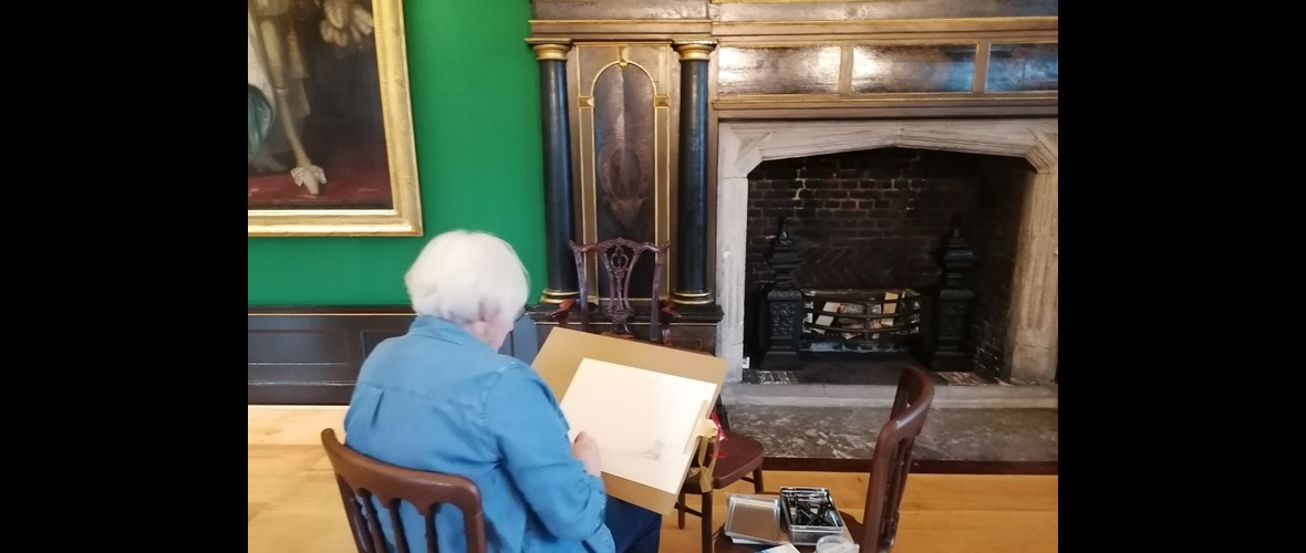 Person with white hair drawing in the Great Chamber