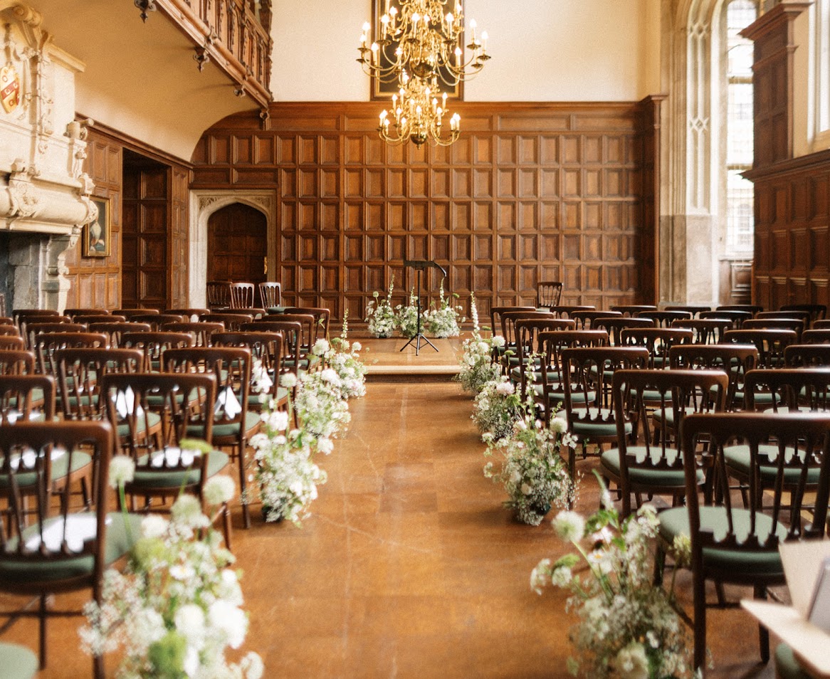 The Great Hall at the Charterhouse set up for a wedding with white flowers on the edge of the aisle