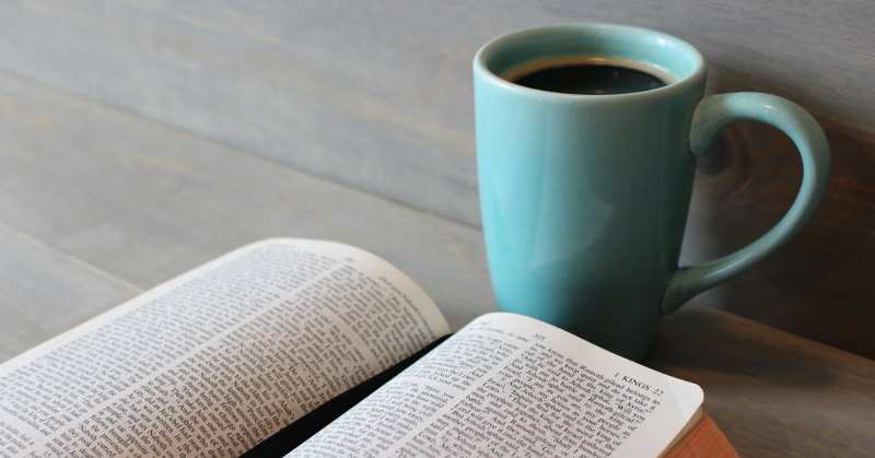 An open Bible beside a cup of coffee