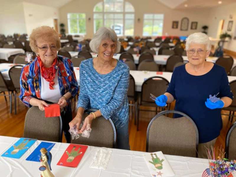 Three Cowee GEMs ladies smiling while preparing cards in the Fellowship Hall