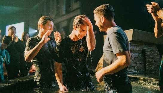 three men standing on black tub full of water