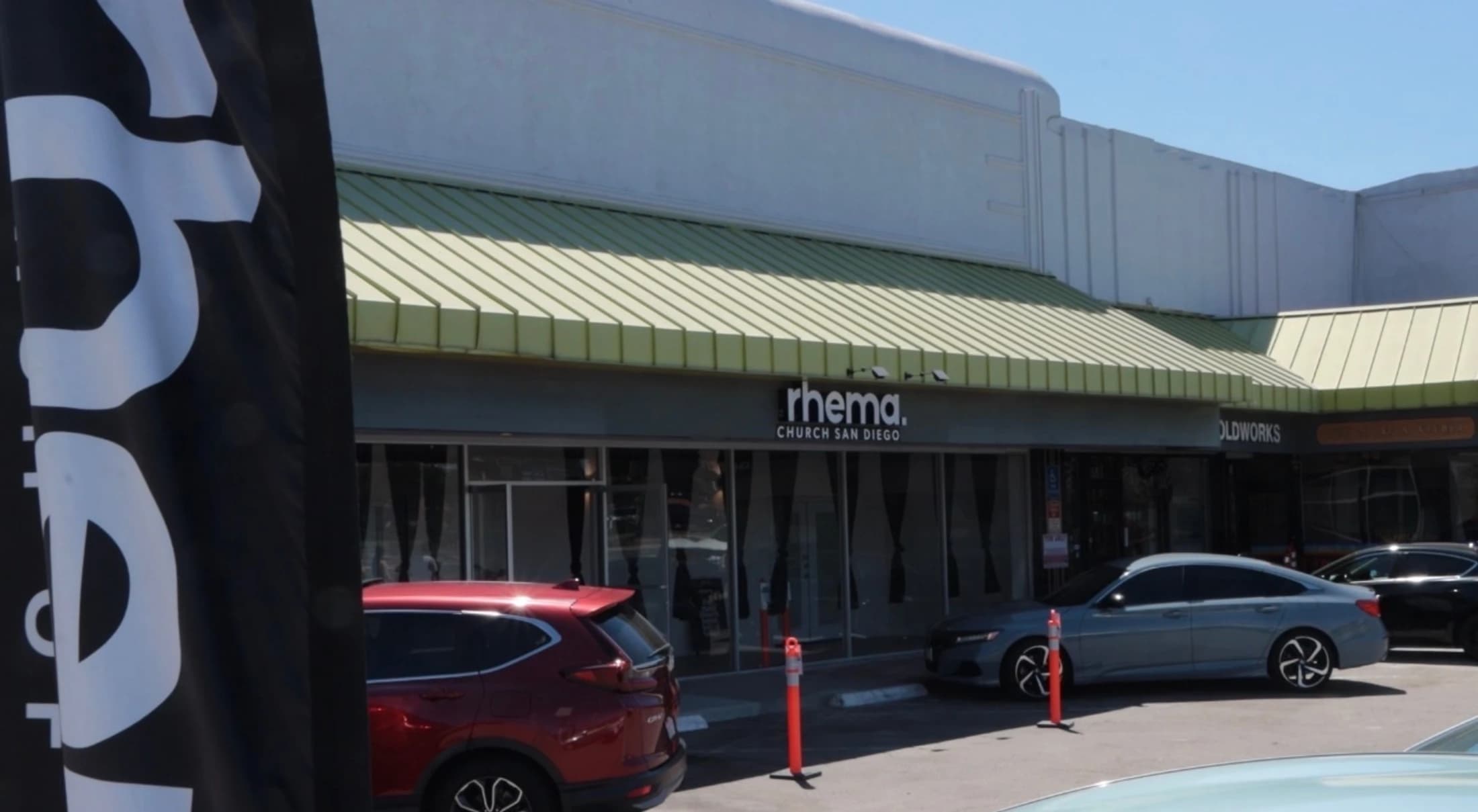 The storefront of Rhema Church San Diego, located in a strip mall with cars parked in front on a sunny day.