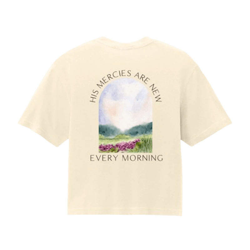 Back of a cream t-shirt with a watercolor graphic of a pastoral landscape framed in an arch. Text reads 'His mercies are new every morning'.
