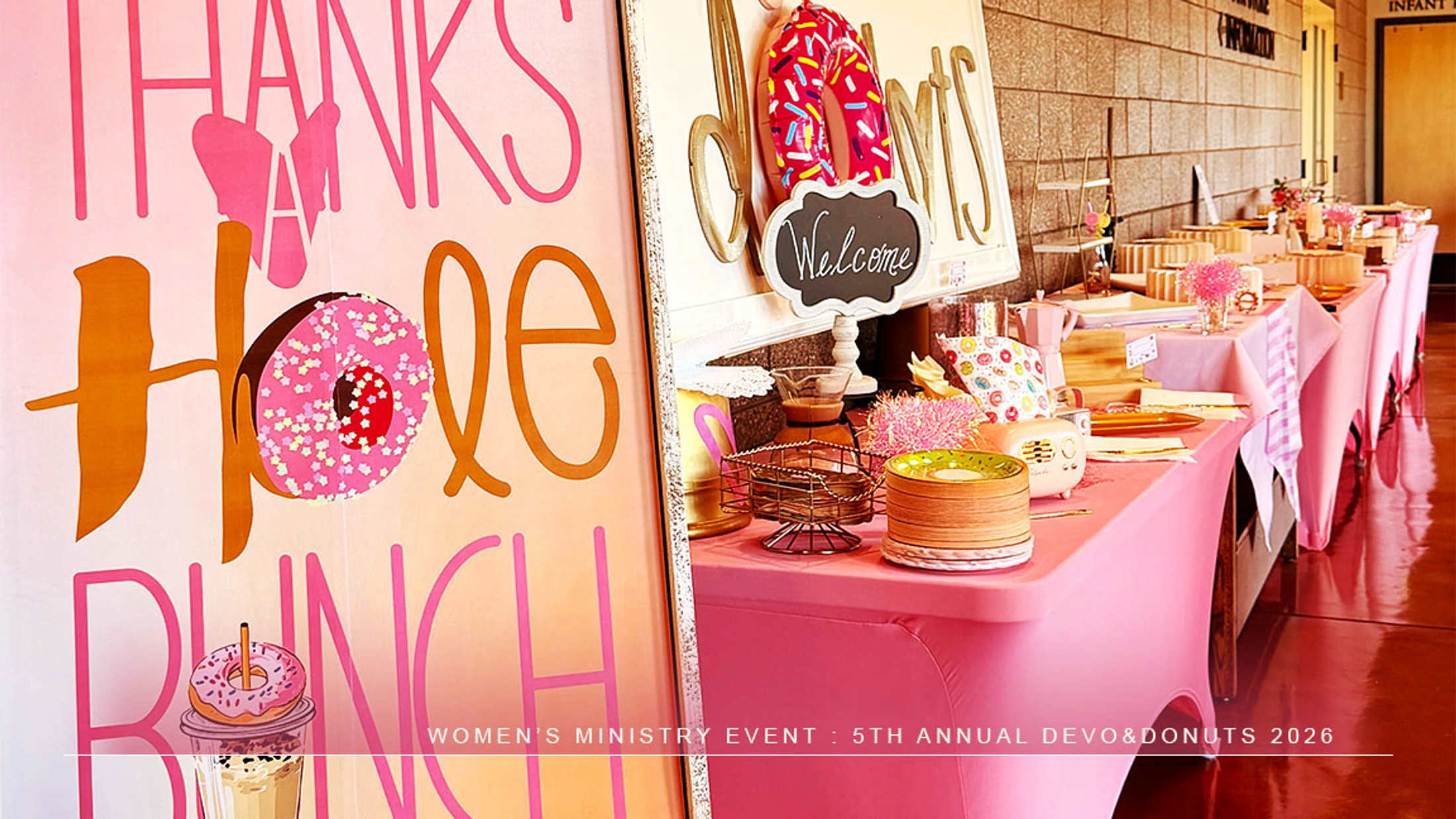 A long table with a pink tablecloth is decorated for a donut-themed party, with a large sign in the foreground reading 'Thanks a Hole Bunch'.