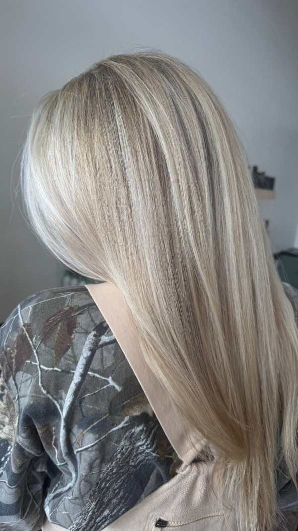 Long straight blonde hair with full highlights and blended lowlights, finished with a smooth salon style.