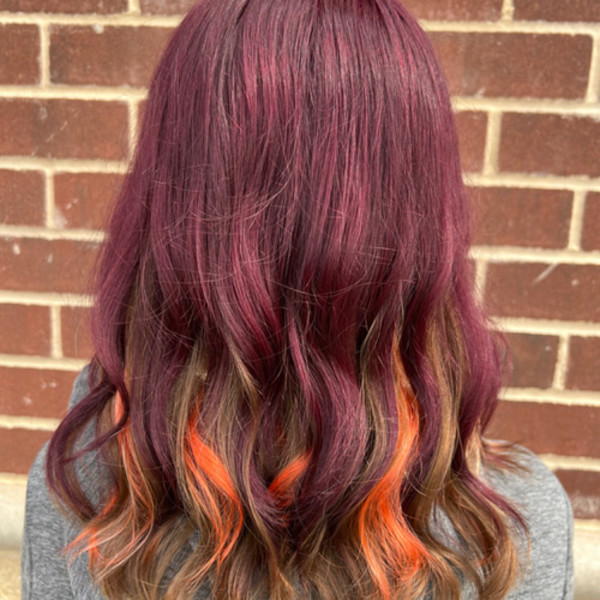 Wavy magenta hair with vibrant orange peekaboo highlights by Green Bay stylist Kassandra Simonar.