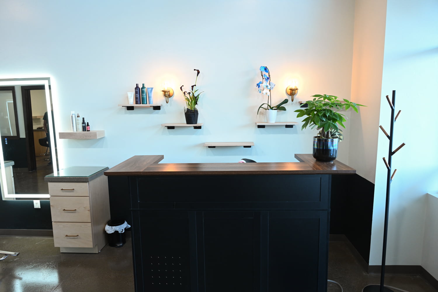 Modern front desk and reception area with product displays inside The Collective luxury hair salon in Green Bay, Wisconsin.