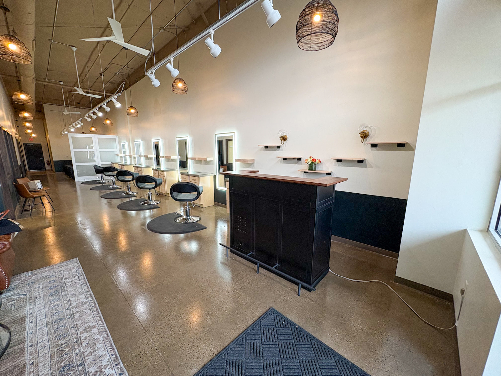 Hair salon in Green Bay WI with modern styling stations, reception desk, and polished concrete floors.
