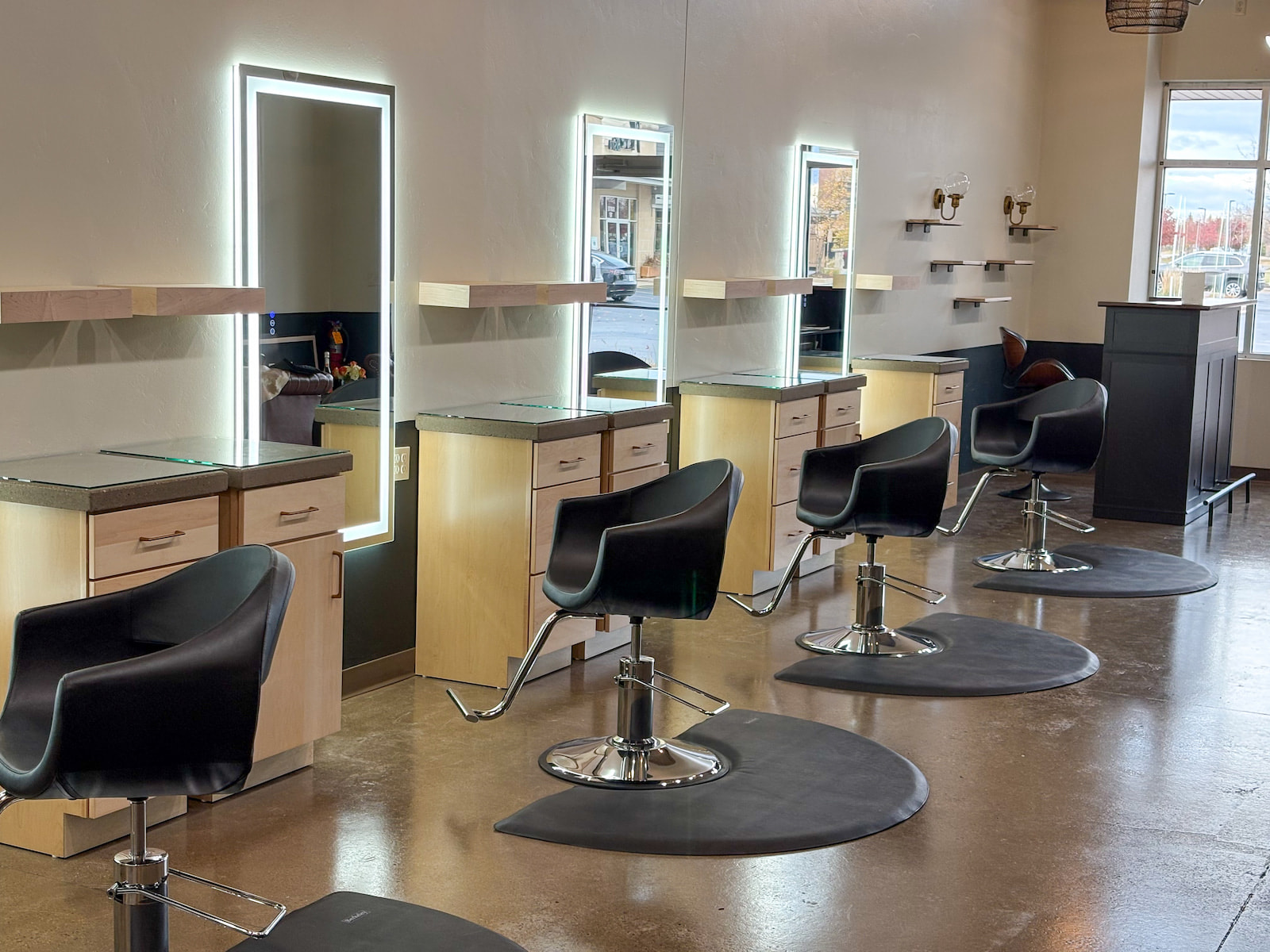 Row of modern salon styling stations with LED mirrors and black chairs in a Green Bay WI hair studio.
