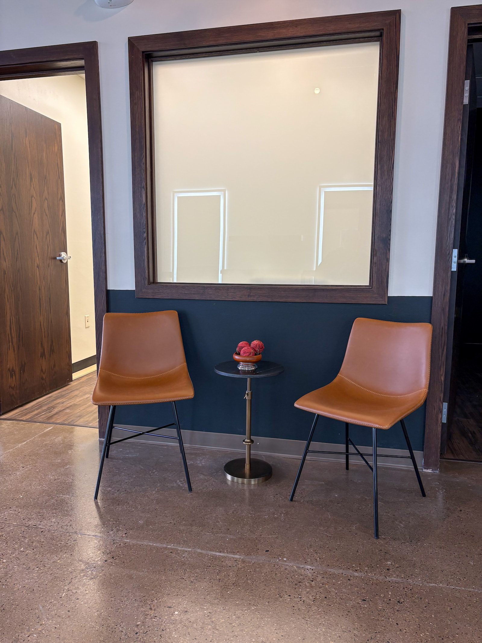 Modern hair salon waiting area in Green Bay WI with two brown chairs and a black side table.