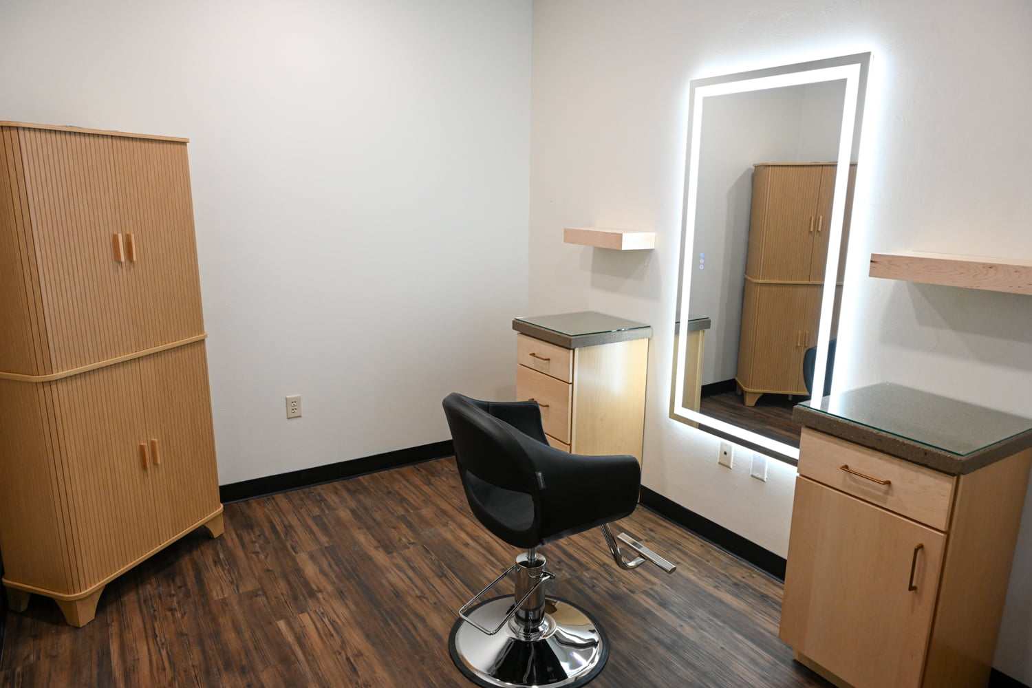 Private styling station with salon chair, illuminated mirror, and custom cabinetry inside The Collective luxury hair salon in Green Bay, Wisconsin.