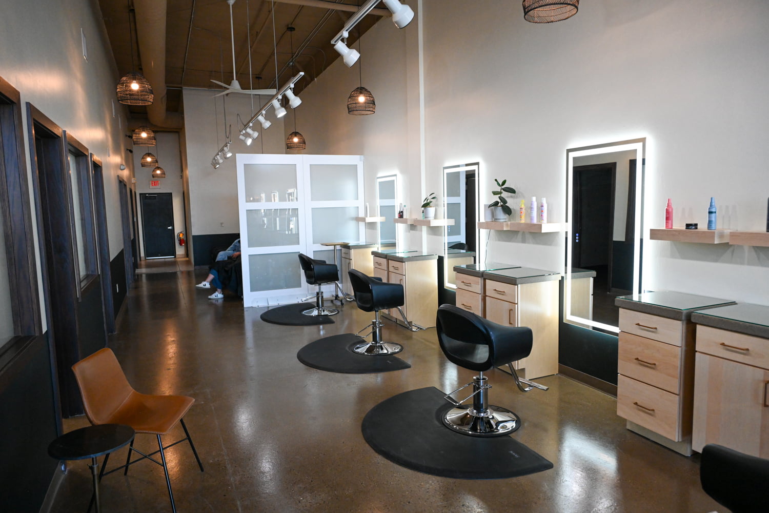 Open styling floor with modern salon chairs, illuminated mirrors, and private stations inside The Collective luxury hair salon in Green Bay, Wisconsin.