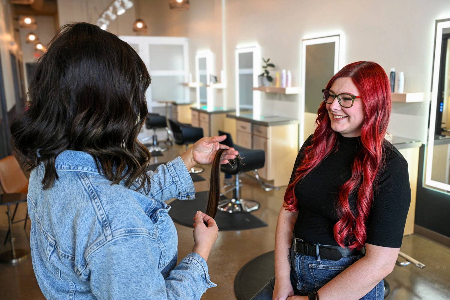 Two hair stylists looking at hair extensions together
