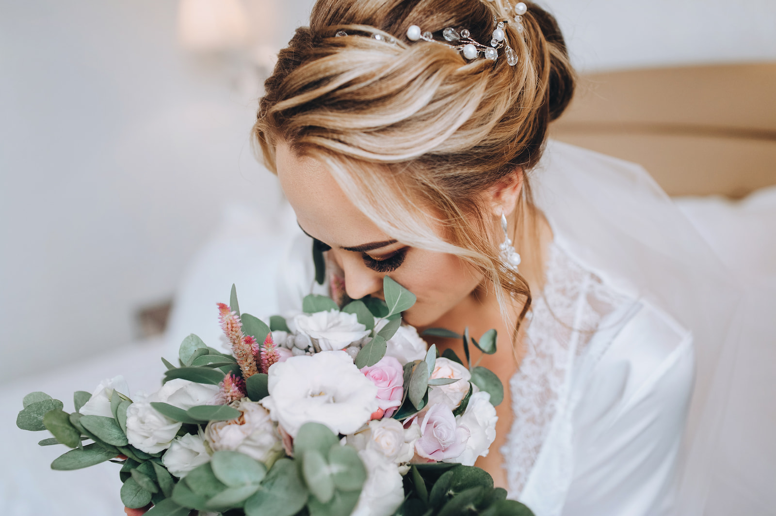 Bride with styled updo and pearl hair accessories holding a pastel flower bouquet in Green Bay, WI.