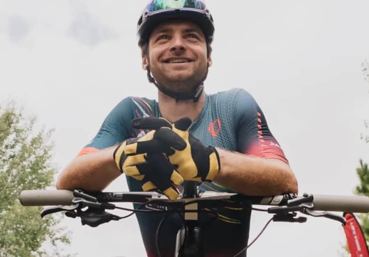 Triathlete in an aero position on a bike, wearing a The Feed aero helmet