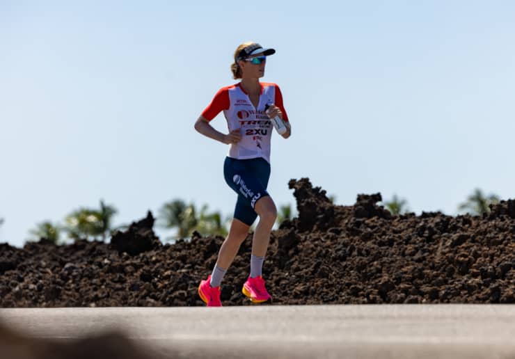 Triathlete in an aero position on a bike, wearing a The Feed aero helmet