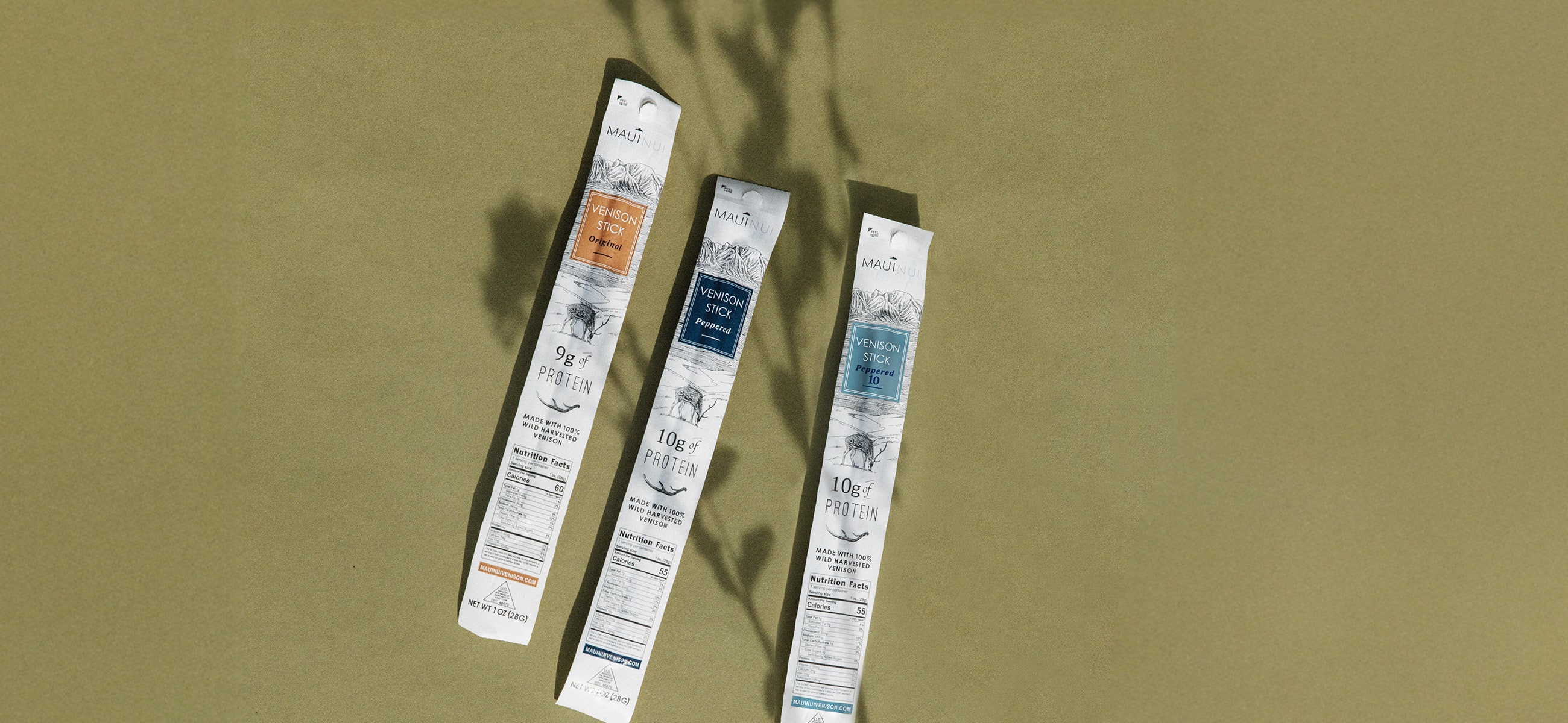 three Maui Nui venizon sticks on a neutral surface with a shadow