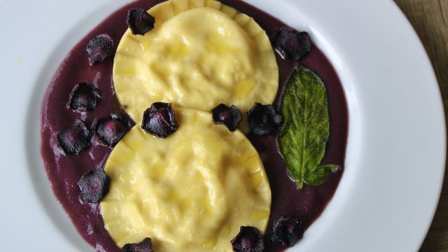 Ravioloni ripieni di ricotta, pecorino, nocciole e zest di limone su purea di carote viola