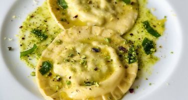Ravioloni ripieni di ricotta e aglio orsino con olio al pistacchio e scorza di limone