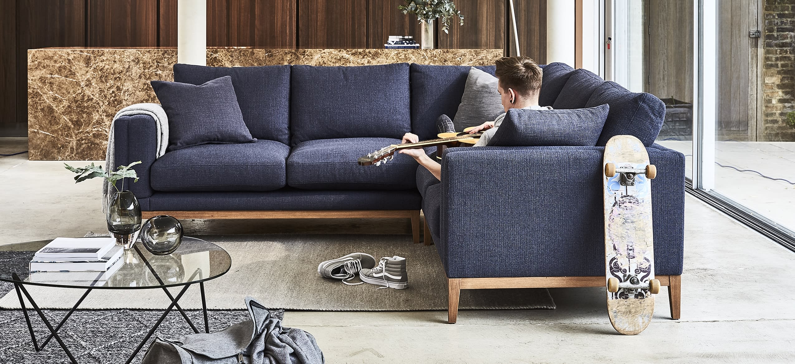 Man playing guitar on a corner sofa