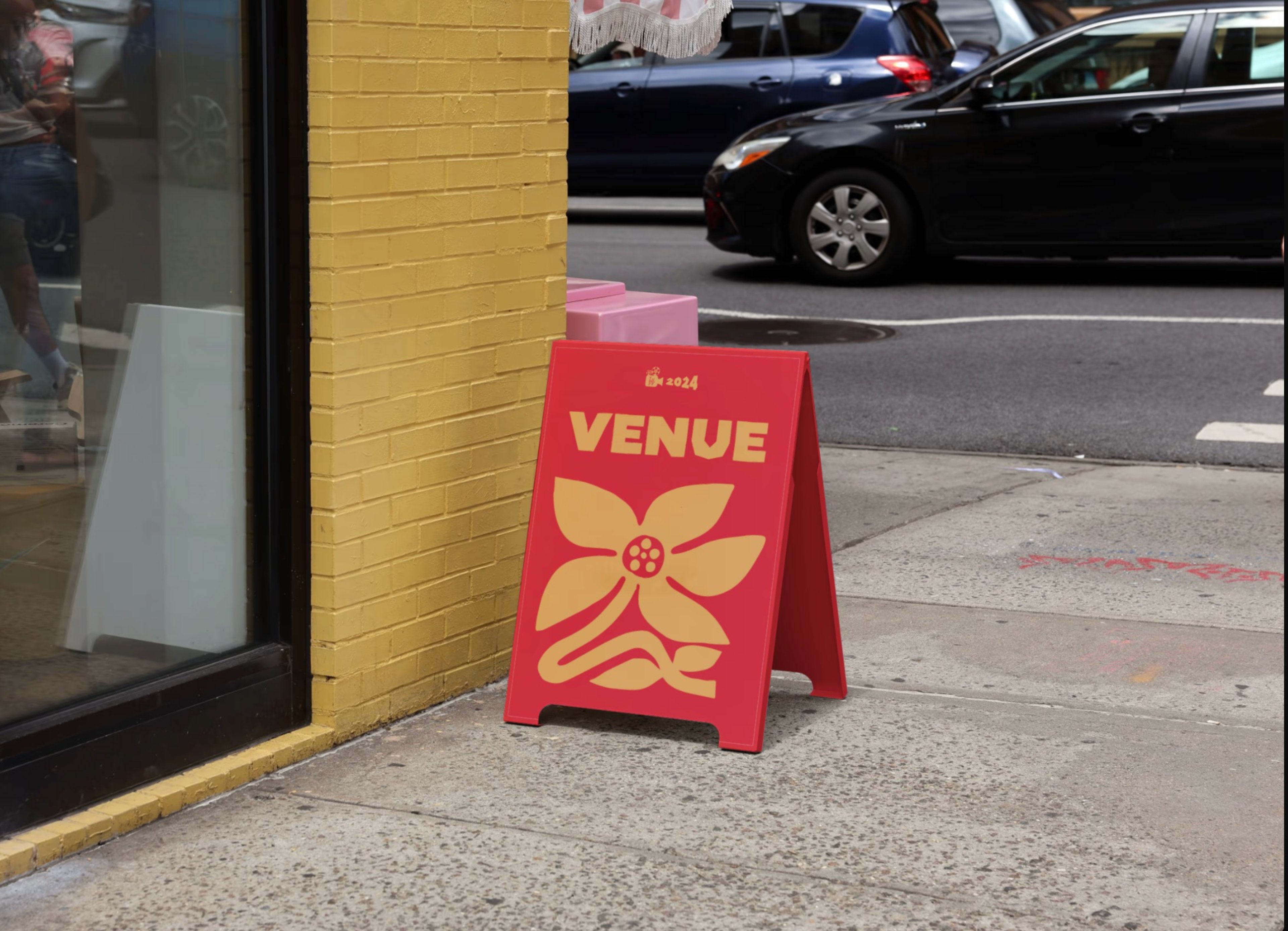 A venue sign for the Michigan State University LatinX Film Festival, its design consists of a singly chunky flower design in yellow on a red backdrop, the center of the flower shows a simplified film reel design