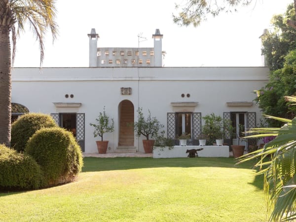 The handsome white façade of Masseria Cisterna Rossa framed by manicured gardens.