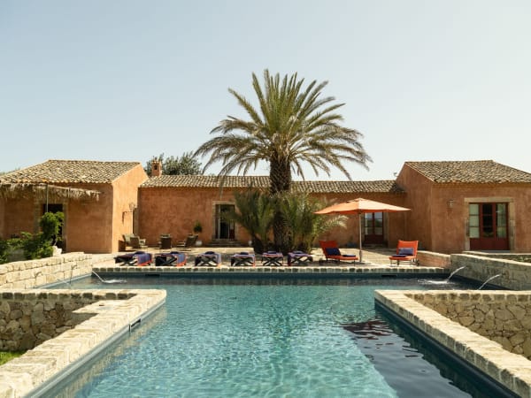 A T-shaped pool, a shady palm tree, burnt orange walls and terracotta roofs: welcome to Arbolì.