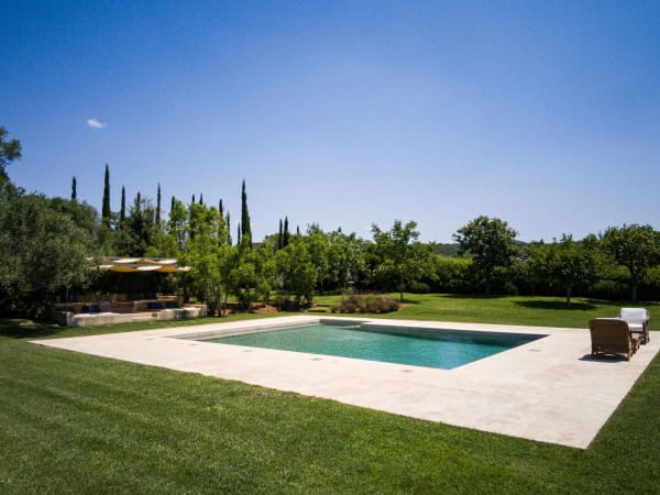 Pristine lawns and mature trees wrap around the pool.